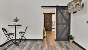 A room with a black-framed table and chairs, a sliding barn-style door, and a mounted picture of a house. - Joe's Place in Historic Wallace, Idaho (Wallace)