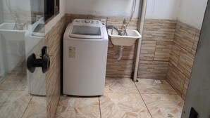 A compact bathroom with a washing machine, a sink, and a window. - Suíte Familiar em Paraty  (Paraty)