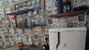 A kitchen with a refrigerator, wooden cabinets, a countertop, and a wall with vintage food and beverage logos. - Suíte Familiar em Paraty  (Paraty)