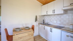 Una cocina compacta con armarios blancos, encimera de madera y estufa integrada.