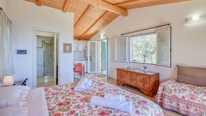 Un dormitorio con dos camas, techo de madera, baño con ducha y zona de comedor.