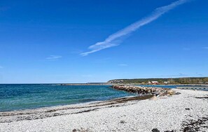 A pebble beach with a rocky breakwater and a clear blue sky.