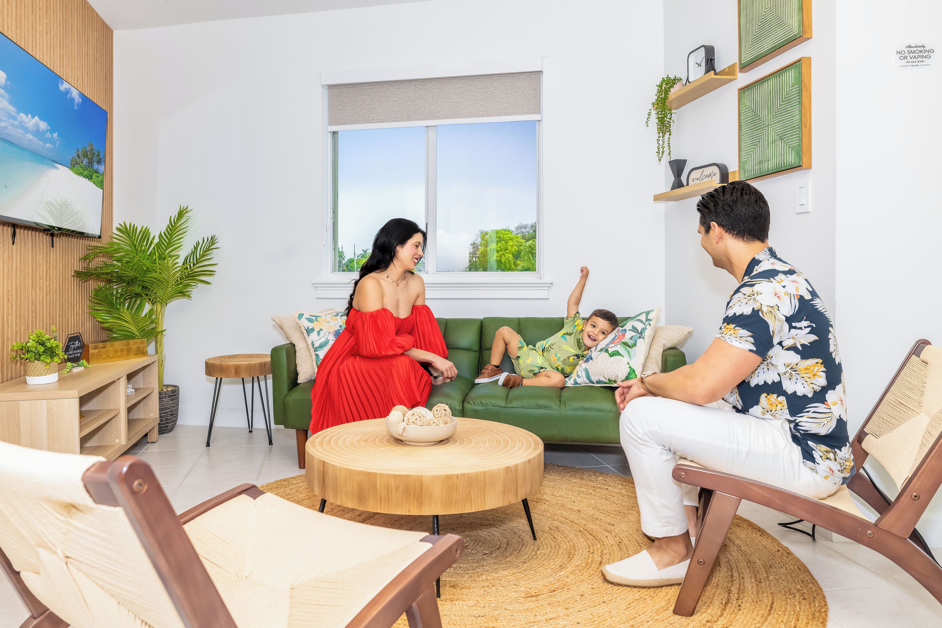 Ein Wohnzimmer mit einem grünen Sofa, einem runden Couchtisch und einem an der Wand befestigten Fernseher.