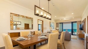 Uma sala de jantar moderna com uma mesa de madeira, cadeiras bege e um espelho grande acima.