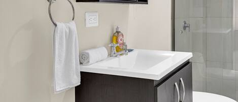 A bathroom with a white sink, dark wooden cabinet, a towel ring, a mirror, and a toilet.
