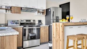 A modern kitchen with stainless steel appliances, wooden cabinets, and a granite countertop.