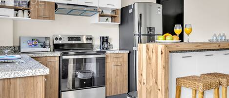 Et moderne køkken med rustfrie hvidevarer, træskabe og en granitbordplade.
