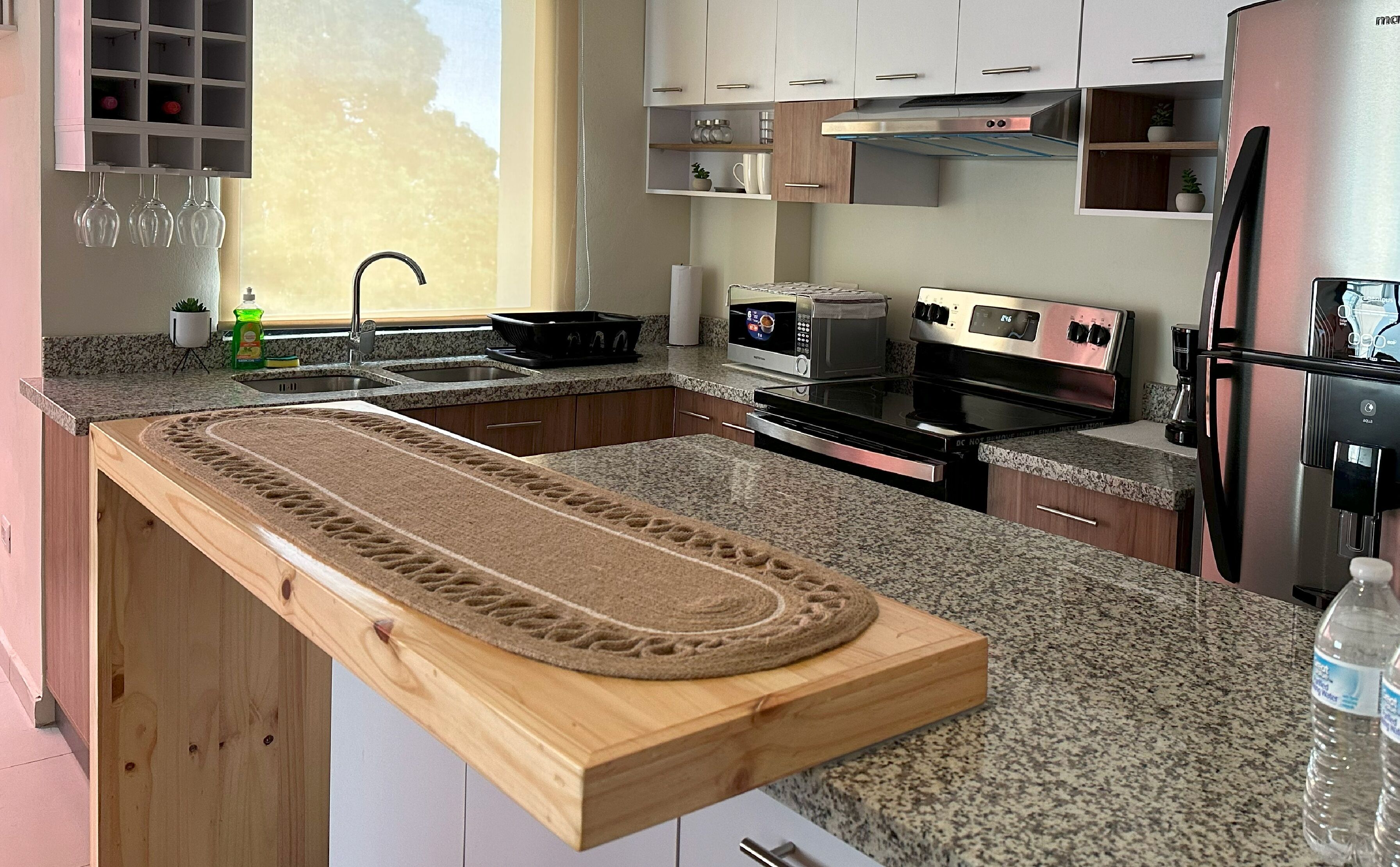 Una cocina moderna con encimeras de granito, electrodomésticos de acero inoxidable y armarios de madera.