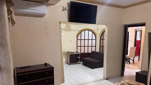 Ein Hotelzimmer mit Bett, Schminktisch, Fernseher und Blick auf den Flur.