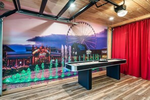 Una stanza con un tavolo da biliardo, un murale con una ruota panoramica e una tenda rossa.