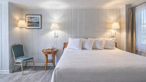 A hotel room with a bed, two bedside lamps, a small table with a chair, and a painting on the wall. - Colony Inn By OYO Columbus US-280 (Columbus)