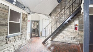 A hallway with stone walls, a tiled floor, and a metal staircase. - Colony Inn By OYO Columbus US-280 (Columbus)