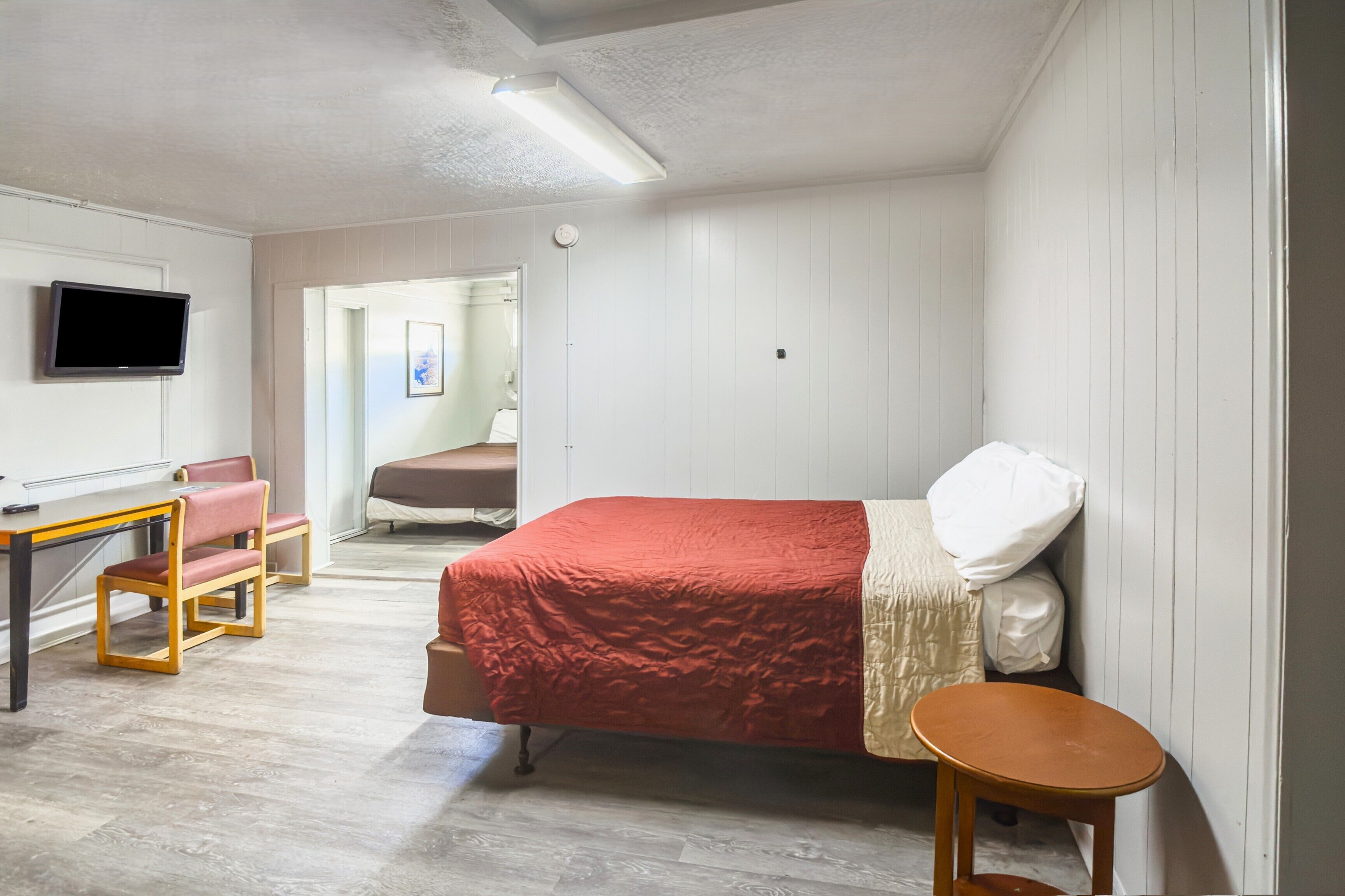 A bedroom with a bed, a desk, a chair, and a television.