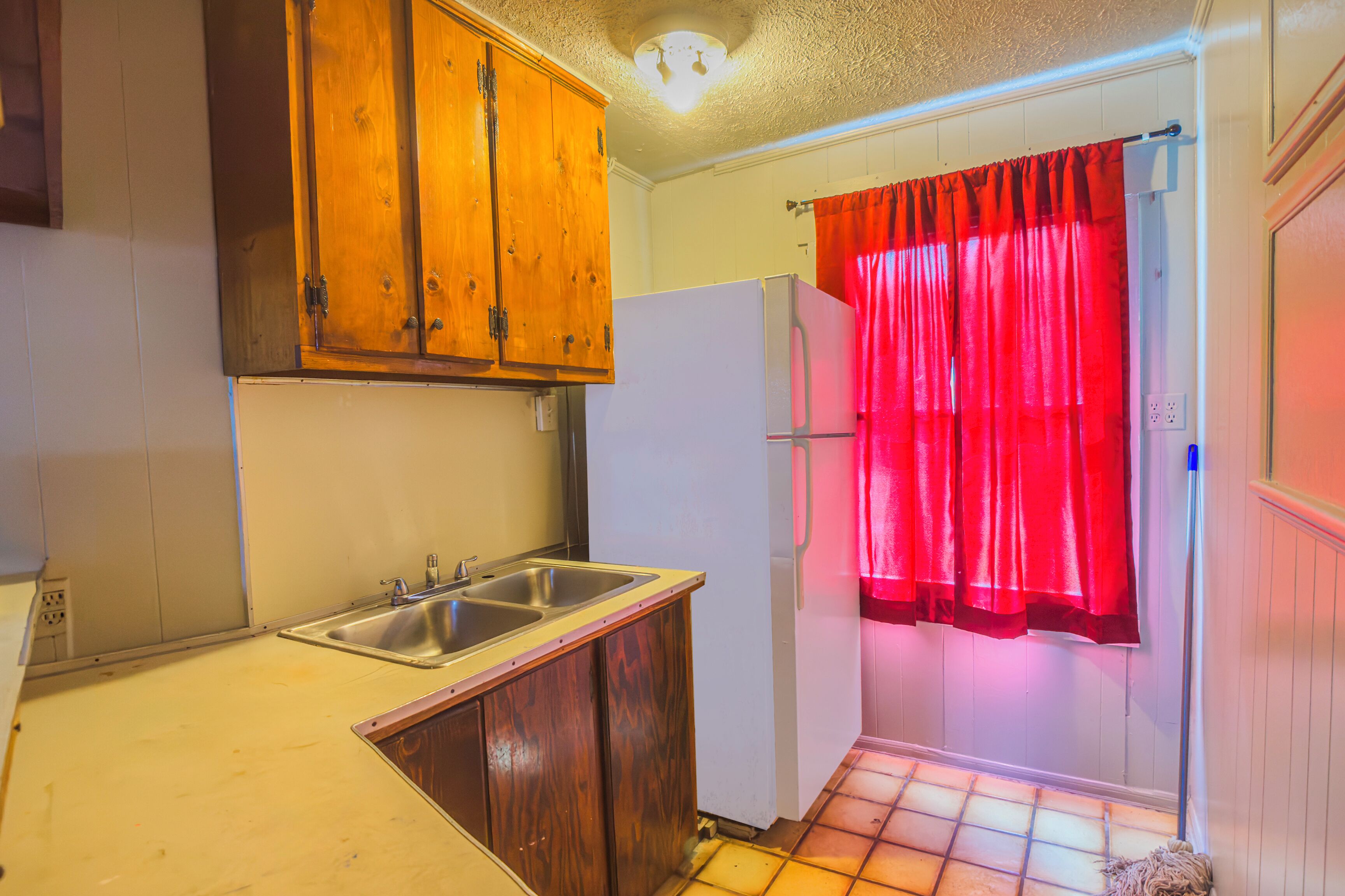 A kitchen with wooden cabinets, a sink, and a refrigerator.