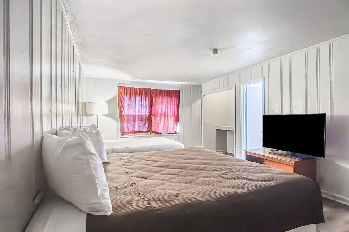 A hotel room with a bed, a television, and a window with curtains.