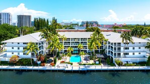 A hotel with a swimming pool, palm trees, and a view of the city skyline. - Boca Waterfront • Walk to Beach • Pool & Hot Tub • Gym • Parking (Boca Raton)