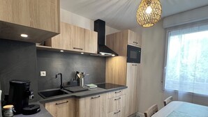 A modern kitchen with wooden cabinets, a black countertop, a built-in stove, and a window with a view of trees. - 1 bedroom private vacation home in albi (Albi)