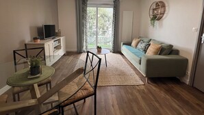 A modern living room with a sofa, a TV on a cabinet, a dining table with chairs, and a large window with curtains. - 1 bedroom private vacation home in albi (Albi)