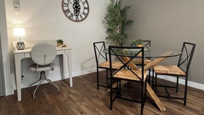 A dining area with a round table, four chairs, a desk with a chair, a wall clock, and a potted plant. - 1 bedroom private vacation home in albi (Albi)
