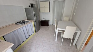 Eine kompakte Küche mit Gasherd, Kühlschrank und einer Essecke mit Tisch und Stühlen.