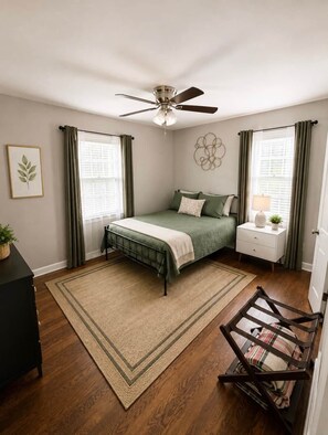 A bedroom with a bed, a nightstand, a lamp, a ceiling fan, and a window with curtains. - Charming Home in Southland – Cozy & Spacious! (Lexington)