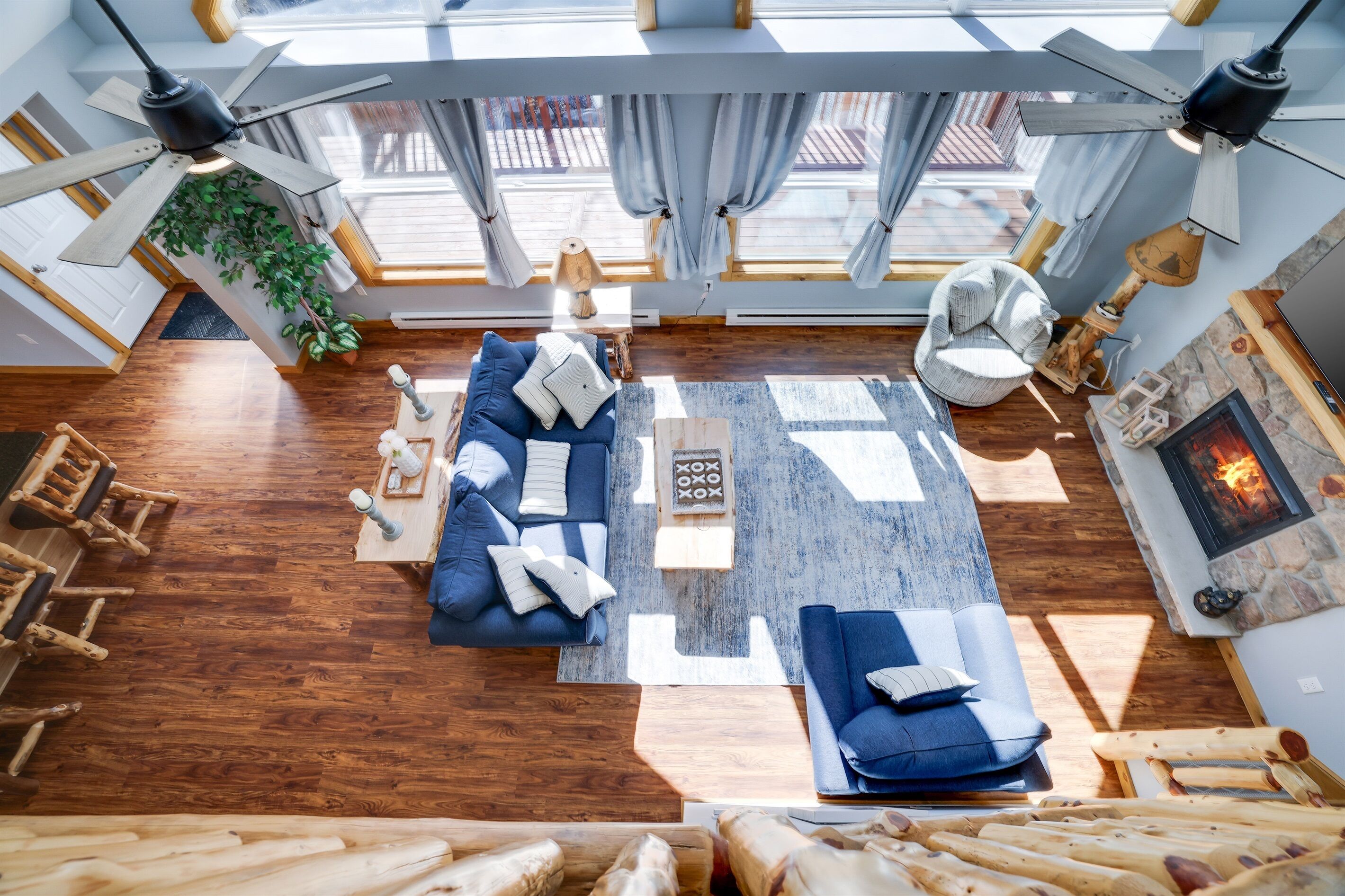 Un salon moderne avec un canapé bleu, un plancher en bois, une cheminée et un ventilateur de plafond.