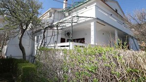 Ein zweistöckiges Haus mit Balkon, umgeben von viel Grün.