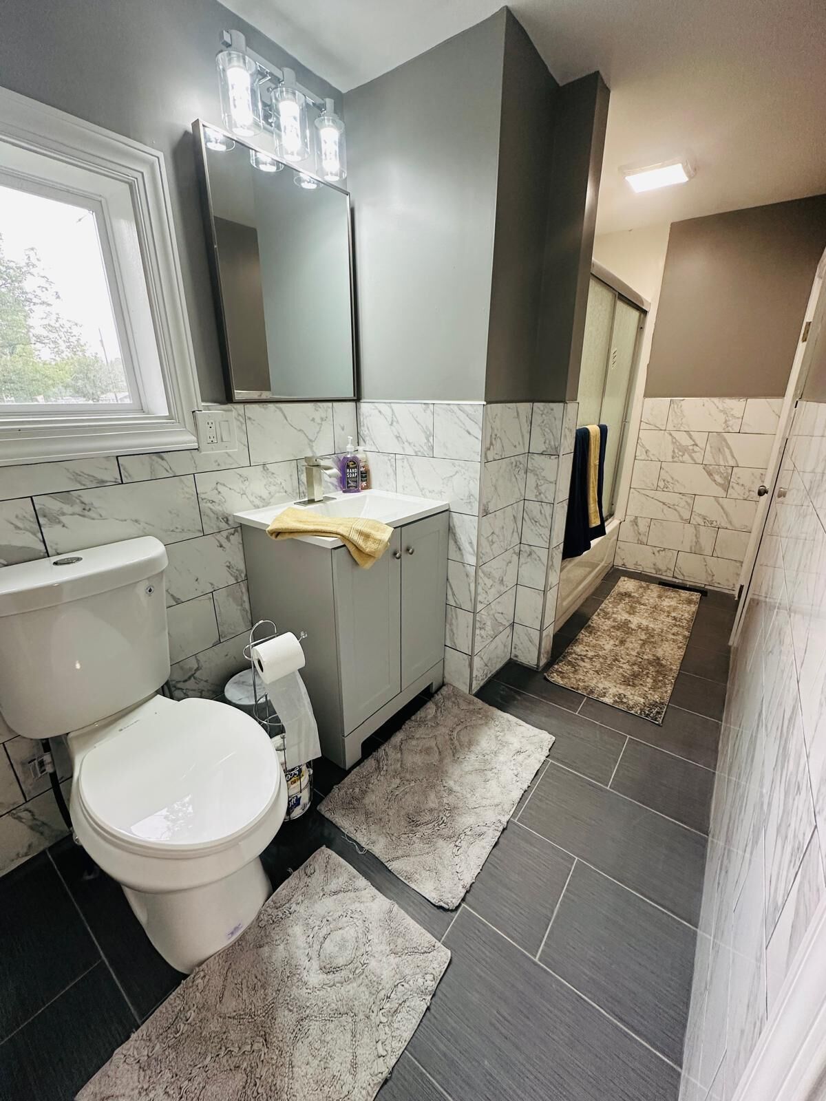 Un baño con inodoro, lavabo, espejo y zona de ducha.