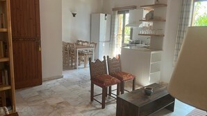 Ampla sala de estar com piso de mármore, móveis de madeira e uma cozinha ao fundo.