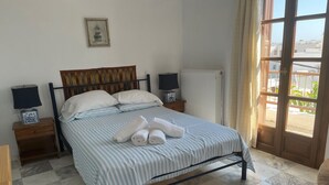Ein Schlafzimmer mit einem Bett, zwei Nachttischen, einer Heizung und Blick durch eine Tür.