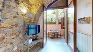 A narrow hallway with a stone wall on one side and a wooden door leading to a balcony.