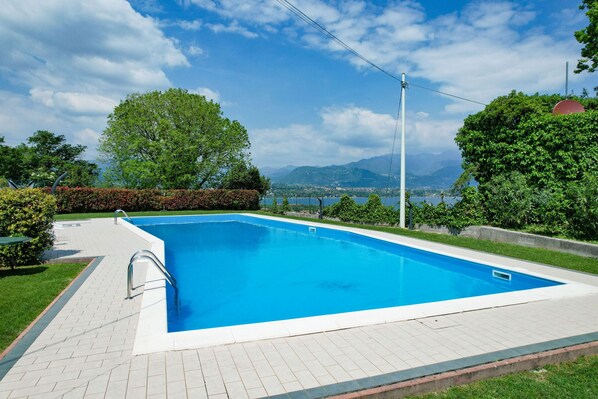 A rectangular swimming pool with a clear blue water surface, surrounded by a paved deck.