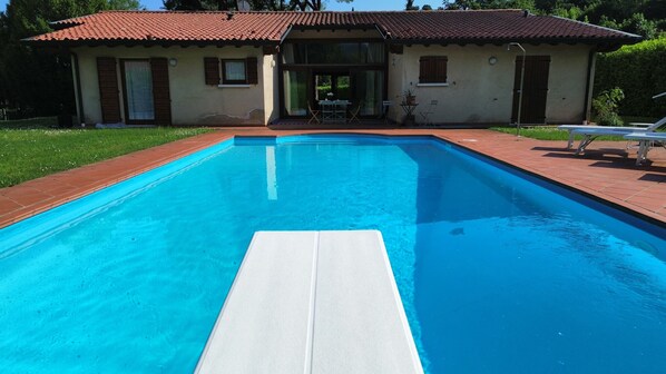 Una piscina con una plataforma blanca flotante en el centro, rodeada por un borde de ladrillo.