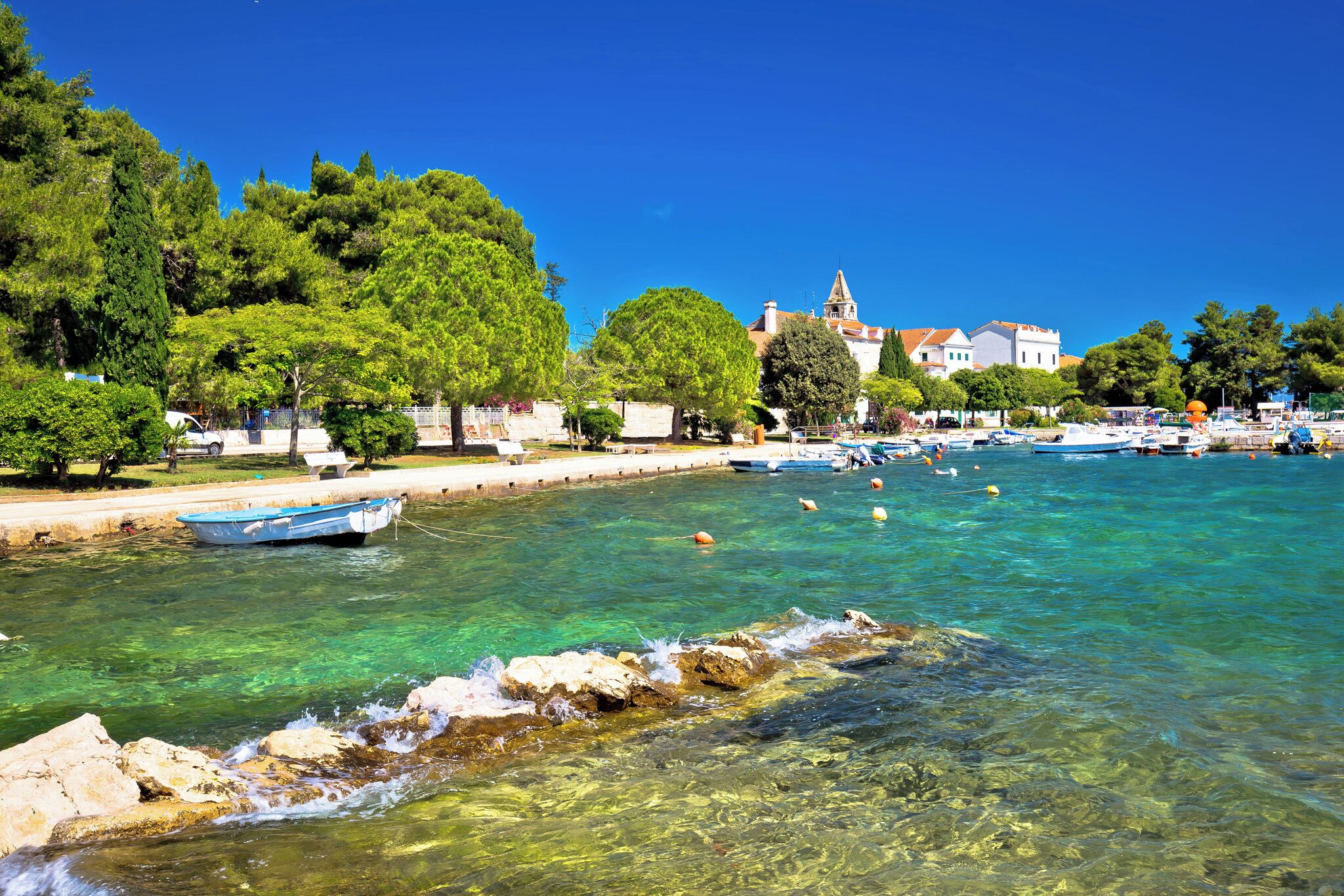 A coastal town with clear waters, boats, and a church in the background.