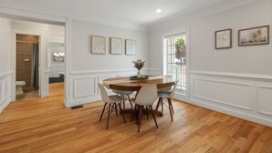 A dining area with a wooden table and chairs, white walls, and framed artwork. - NEW!! Cozy Arlington Home Near DC (Arlington)