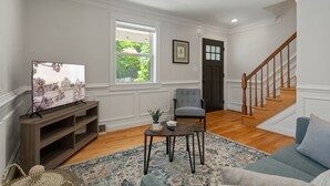 A living room with a television, a chair, a sofa, a rug, and a staircase. - NEW!! Cozy Arlington Home Near DC (Arlington)