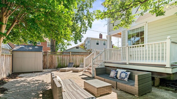 A backyard with wicker furniture, a wooden deck, and a staircase leading to a covered area. - NEW!! Cozy Arlington Home Near DC (Arlington)