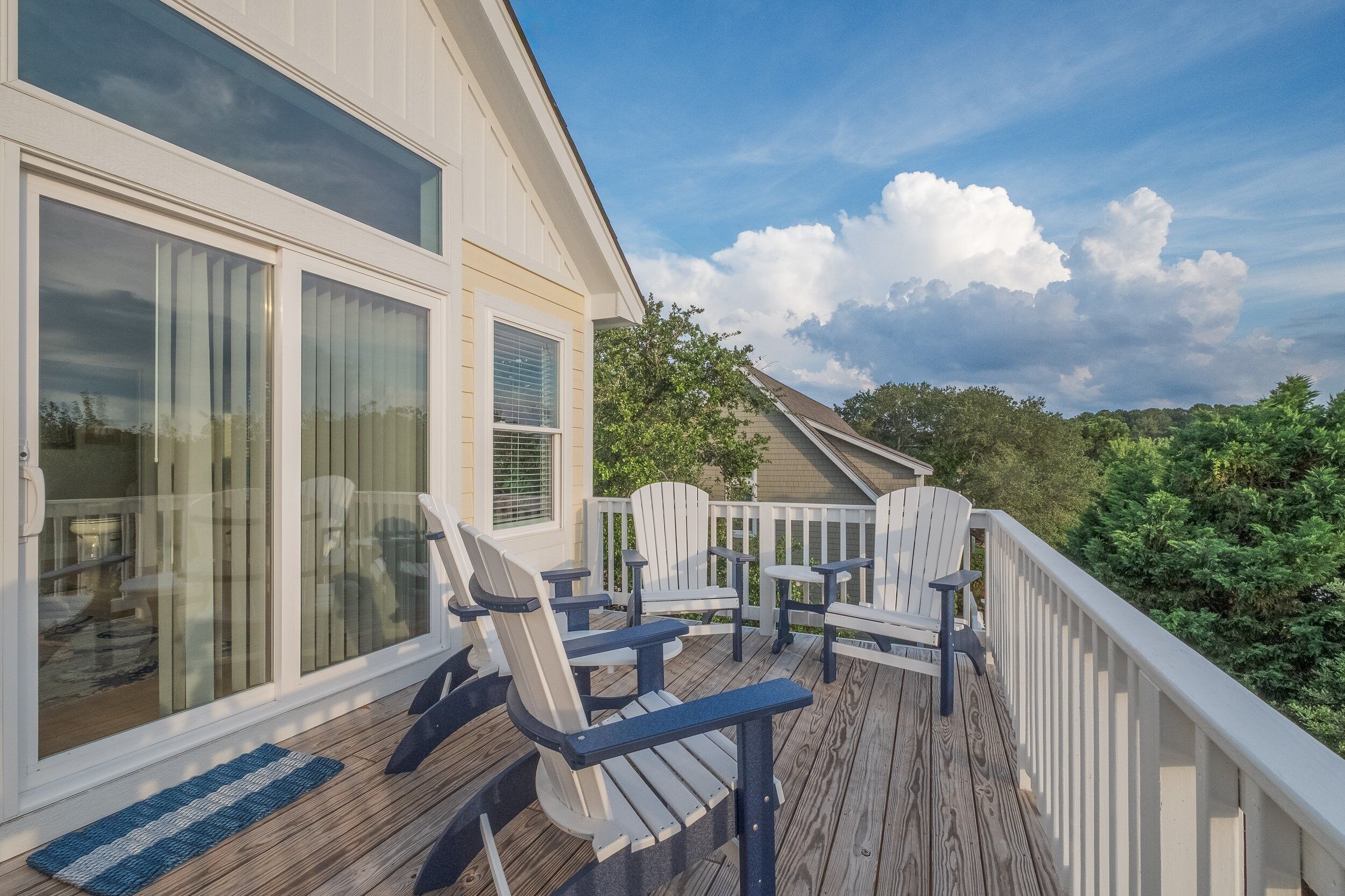 Une terrasse dotée de chaises Adirondack et d’un plancher en bois, offrant une vue sur un paysage verdoyant luxuriant.