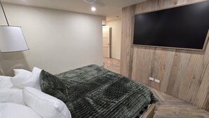 Une chambre à coucher avec un lit, un téléviseur fixé au mur et un ventilateur de plafond.