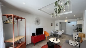 A modern living room with a TV, red and white furniture, a dining area, and a kitchen. - Port-Fréjus, 400m from the beaches, cozy 28m2 studio, air conditioning, terrace, private parking, ideal for 2 people (Fréjus)