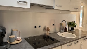 A modern kitchen with a built-in stove, a sink, and white cabinets. - Port-Fréjus, 400m from the beaches, cozy 28m2 studio, air conditioning, terrace, private parking, ideal for 2 people (Fréjus)