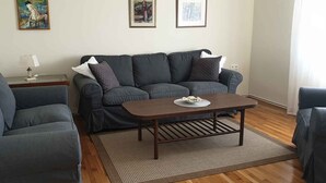 Ein Wohnzimmer mit grauem Sofa, einem Holztisch und einem gemusterten Teppich.