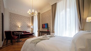 Une chambre d’hôtel avec un grand lit, un bureau avec une chaise, un canapé et un téléviseur fixé au mur.