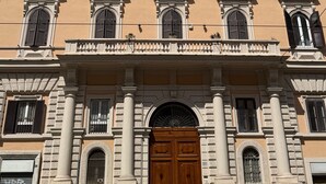 Un immeuble à plusieurs étages doté d’une entrée centrale, de grandes fenêtres et d’un balcon.