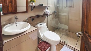 A modern bathroom with a sink, toilet, and shower. There is a mirror above the sink and a shelf with toiletries. -  Volcano and Lake View, Eco Glam #1. (La Fortuna)