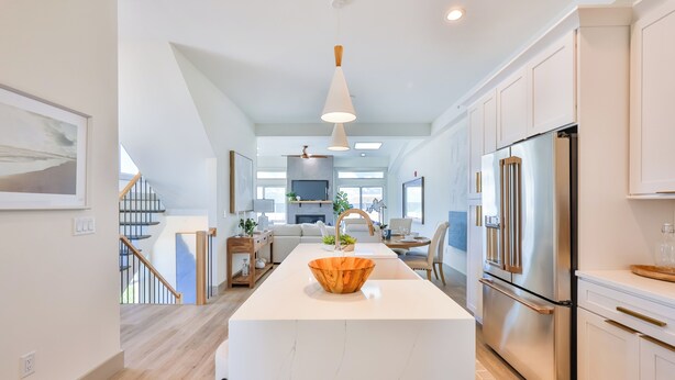 Une cuisine moderne dotée d’un îlot central, d’appareils électroménagers en acier inoxydable et d’un saladier en bois servant de pièce maîtresse décorative.