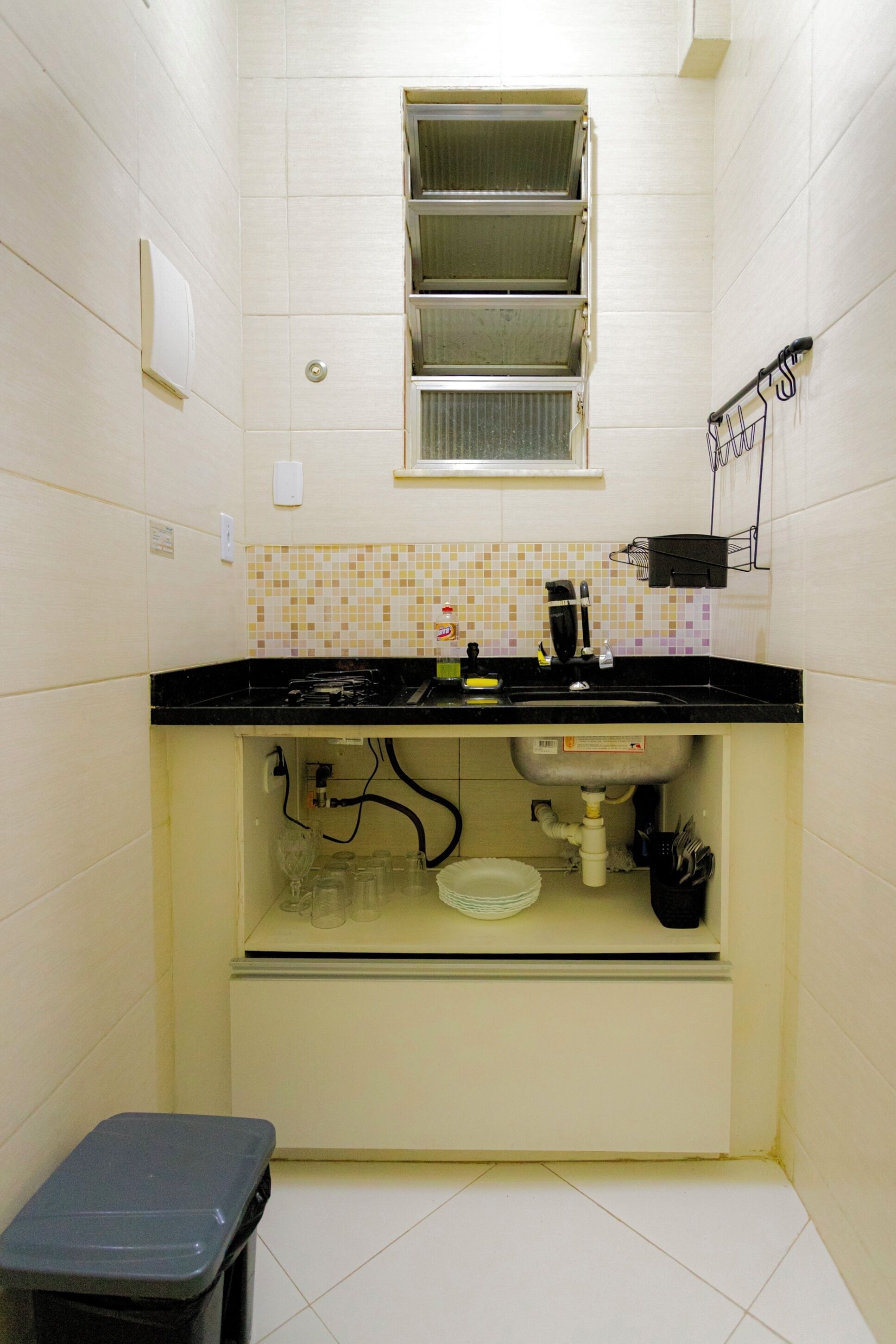 A small kitchen with a black countertop, a window above the sink, and a tiled backsplash.