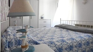 Une chambre à coucher comprenant un lit, une table de chevet, une lampe et une étagère fixée au mur.