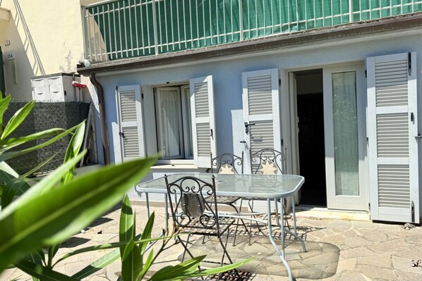 Un bâtiment doté d’un balcon, d’une table avec des chaises et d’une porte.