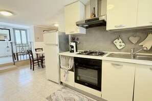 Une cuisine moderne équipée d’une cuisinière à gaz, d’un four et de meubles de rangement blancs.